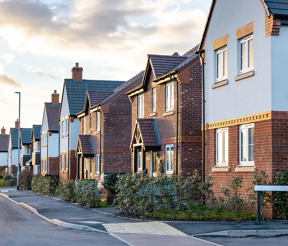 Row of modern suburban houses along a quiet residential street at sunset.